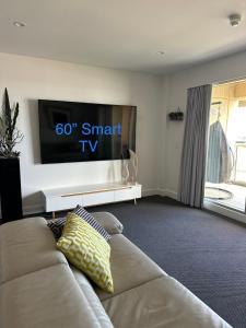 a living room with a couch and a flat screen tv at Absolute Beachfront at the Pier Glenelg in Adelaide