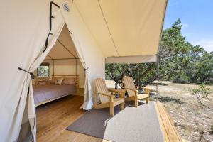 a tent with two chairs and a bed in it at Twin Falls Luxury Glamping - Cozy Retreat in Boerne +21 photos