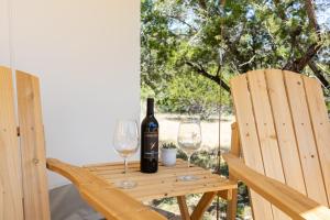 Una botella de vino y dos copas en una mesa de madera. en Twin Falls Luxury Glamping - Cozy Retreat, en Boerne