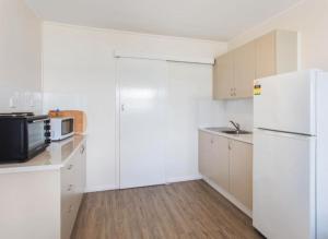 a kitchen with white cabinets and a white refrigerator at Lakeside 4 in Tuncurry