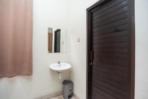 a bathroom with a sink and a black door at RedDoorz Plus near RS PMI Bogor in Bogor