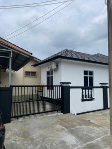 a white house with a black fence in front of it at 13 Avenue Homestay in Kota Bharu