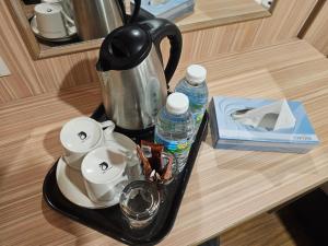 a tray with a tea kettle and cups and water at Veer Hotel in Kuantan