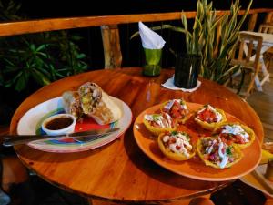 einem Holztisch mit zwei Teller Essen drauf in der Unterkunft Monkey House Hostel in Tola