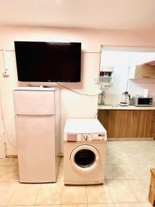 a washing machine in a kitchen with a tv on the wall at КВАРТИРА ВОЗЛЕ БАХАЙСКИХ САДОВ! in Haifa