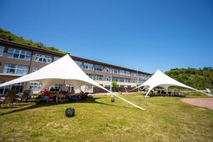 two white tents on a field in front of a building at KIBOTCHA/キボッチャ in Higashimatsushima