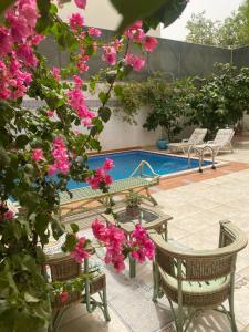 una piscina con due sedie e fiori rosa di Sapphire a Riyad