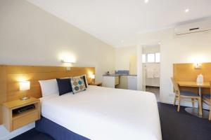 1 dormitorio con 1 cama blanca grande y escritorio en Hamilton Townhouse Motel, en Hamilton