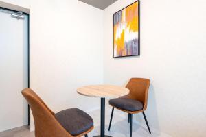 a table and two chairs in a room with a painting at uGard Shimomaruko in Tokyo