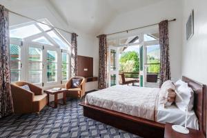 a hotel room with a bed and chairs and windows at StayVista at Gaash Cottage - Pet Friendly Villa with Lawn, Bonfire, WiFi in Sonāmarg