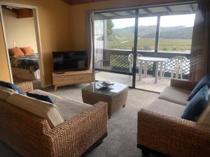 a living room with a couch and a television and a balcony at The Retreat in Paihia
