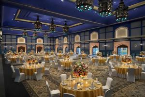 a banquet hall with tables and chairs and chandeliers at Fairmont Jaipur in Jaipur