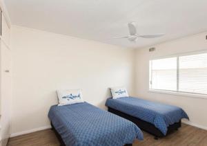 a bedroom with two beds and a ceiling fan at Lakeside 5 in Tuncurry