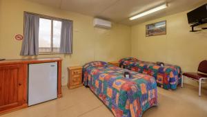 une chambre avec deux lits et une télévision dans l'établissement White Cliffs Hotel, à White Cliffs