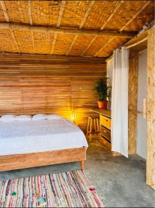 1 dormitorio con 1 cama y pared de madera en El Mirador de Máncora, en Máncora