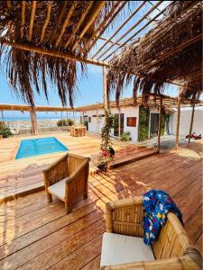 una terraza de madera con 2 sofás y una piscina en El Mirador de Máncora en Máncora