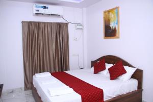1 dormitorio con 1 cama con almohadas rojas y blancas en ELL Parasio, en Port Blair