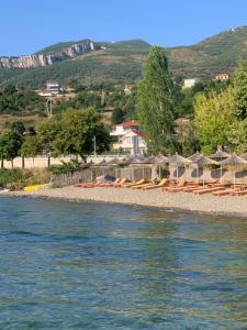 einen Strand mit Stühlen und Sonnenschirmen neben dem Wasser in der Unterkunft Villa Rejan in Pogradec