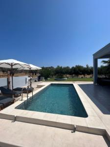 a swimming pool in a house with an umbrella at MG luxury villa kalithies in Kalithies