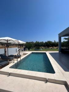 a swimming pool in a house with an umbrella at MG Villa Rhodes in Kalithies