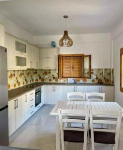 a kitchen with white cabinets and a table and chairs at Dhermi Village Apartments in Dhërmi