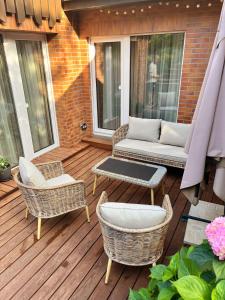 eine Terrasse mit einem Sofa und Stühlen auf einer Terrasse in der Unterkunft Kopų terasos in Nida