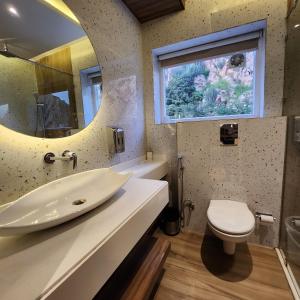 a bathroom with a sink and a toilet and a mirror at Alwar Vanyaevilas in Alwar