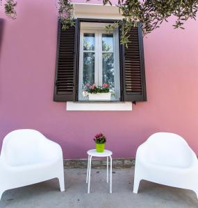 2 Stühle und ein Tisch vor einer rosa Wand in der Unterkunft Miss Sicily B&B in Terrasini