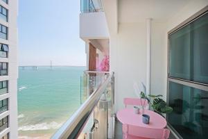 a balcony with a pink table and a view of the ocean at Elmomento Gwangan in Busan