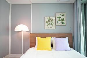 a bedroom with a bed with yellow and white pillows at Elmomento Gwangan in Busan