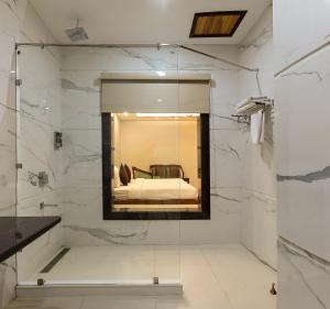 a bathroom with a glass shower with a bed at Hotel Leela Grande in Karnāl