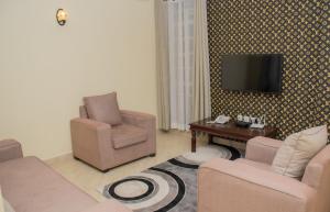 a living room with two chairs and a tv on a wall at Pearl Suites Apartments in Nakuru