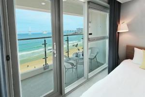 a bedroom with a bed and a view of the beach at Elmomento Gwangan in Busan