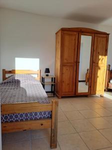 une chambre avec un lit et une armoire en bois dans l'établissement TI CASE TRANQU'ILE OTE !, à Saint-Pierre