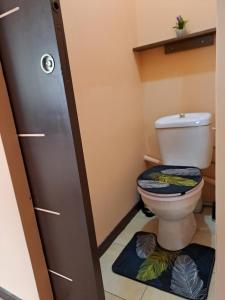 La salle de bains est pourvue de toilettes avec un siège bleu. dans l'établissement TI CASE TRANQU'ILE OTE !, à Saint-Pierre