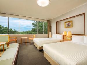 una camera d'albergo con due letti e una finestra di KAMENOI HOTEL Kamogawa a Kamogawa