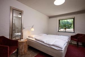 a bedroom with a bed and a mirror and a chair at Jägerhuset in Maribo