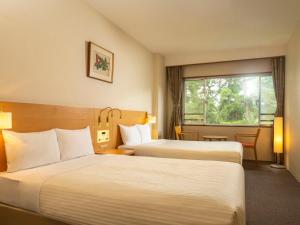 una camera d'albergo con due letti e una finestra di KAMENOI HOTEL Kamogawa a Kamogawa