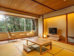 un soggiorno con tavolo, sedie e TV di KAMENOI HOTEL Kamogawa a Kamogawa