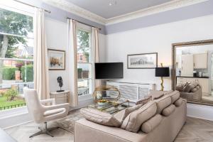 a living room with a large couch and a chair at 10 Sydenham - By Luxury Apartments in Cheltenham