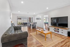 Una sala de estar con un sofá, un televisor y una mesa. en Jakes Place, en Dunsborough