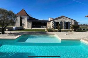 a large blue swimming pool in front of a house at Demeure charentaise Standing - Grande Piscine - jacuzzi balnéo - Pool house in Barbezieux-Saint-Hilaire