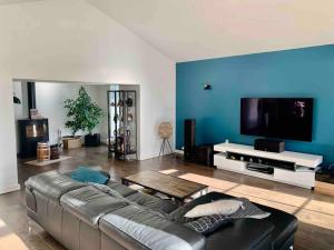 a living room with a couch and a flat screen tv at Demeure charentaise Standing - Grande Piscine - jacuzzi balnéo - Pool house in Barbezieux-Saint-Hilaire