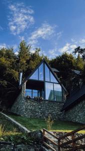 ein Haus mit Glasfenstern an einer Steinmauer in der Unterkunft Columbus Villas in Vermosh