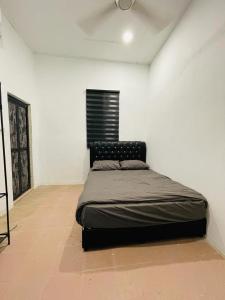 Ce lit se trouve dans un dortoir doté d'un mur blanc. dans l'établissement Casaria Inn Paka, à Paka