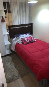 Una cama con sábanas rojas y almohadas rosas. en HOsTAL PALMED, en Concepción
