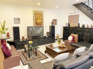 a living room with couches and a flat screen tv at Sunny Dala villa in Nong Prue