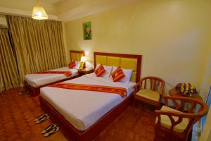 a hotel room with two beds and a chair at Gold Yadanar Hotel in Mandalay