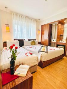 a bedroom with two beds and a table with a book at Elite Central Hotel Hanoi in Hanoi