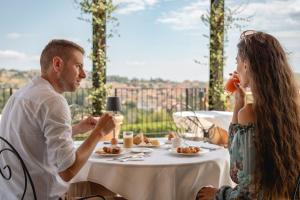 un hombre y una mujer sentados en una mesa comiendo comida en Monvì Wine Relais, en Costigliole dʼAsti
